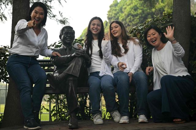 Peru's presidential candidate for the Fuerza Popular party, Keiko Fujimori (L), her sister Sachi (R) and her daughters Kyara (2-R) and Kaori (2-L), pose with the statue of her father, Peru's former President (1990-200) Alberto Fujimori's, at the Campo Fe de Huachipa cemetery, where his remains are buried, in the east of Lima on April 12, 2026, during the presidential election. Peruvians will elect a new president from a record field of 35 candidates to lead a country plagued by organized crime and chronic political instability. (Photo by ERNESTO BENAVIDES / AFP)