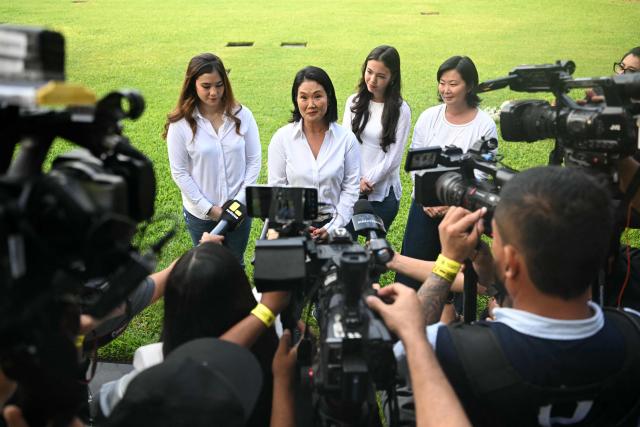 Peru's presidential candidate for the Fuerza Popular party, Keiko Fujimori (2-R), her sister Sachi (R) and her daughters Kyara (L) and Kaori (2-R), are surrounded by journalists at the cemetery where her father, Peru's former President (1990-200) Alberto Fujimori's remains are buried, at the Campo Fe de Huachipa cemetery, in the east of Lima on April 12, 2026, during the presidential election. Peruvians will elect a new president from a record field of 35 candidates to lead a country plagued by organized crime and chronic political instability. (Photo by ERNESTO BENAVIDES / AFP)