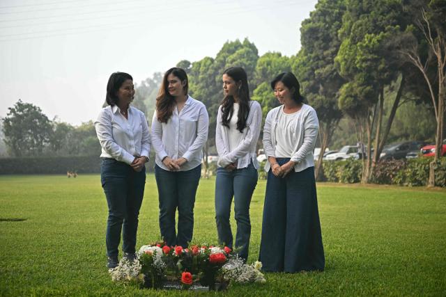 Peru's presidential candidate for the Fuerza Popular party, Keiko Fujimori (L), her sister Sachi (R) and her daughters Kyara (2-L) and Kaori (2-R), pose with the statue of her father, Peru's former President (1990-200) Alberto Fujimori's, at the Campo Fe de Huachipa cemetery, where his remains are buried, in the east of Lima on April 12, 2026, during the presidential election. Peruvians will elect a new president from a record field of 35 candidates to lead a country plagued by organized crime and chronic political instability. (Photo by ERNESTO BENAVIDES / AFP)