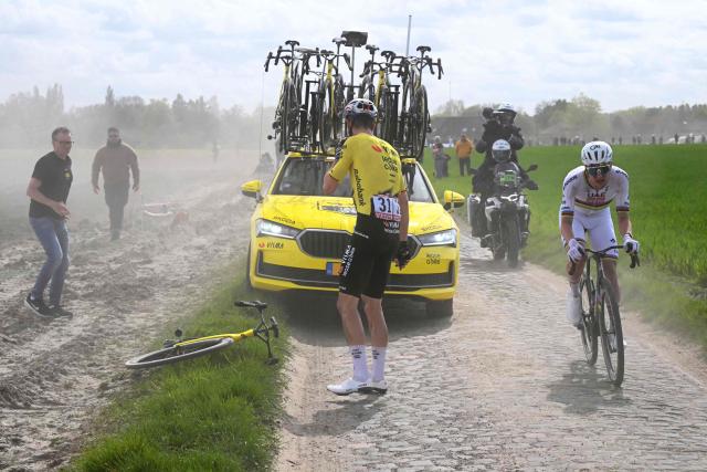 Team Visma - Lease a Bike's Belgian rider Wout van Aert changes his bike after a flat tire next to UAE Team Emirates XRG's Slovenian rider Tadej Pogacar (R) during the 123rd edition of the Paris-Roubaix one-day classic cycling race, 258.3 km between Compiègne and Roubaix, northern France, on April 12, 2026. (Photo by Etienne GARNIER / POOL / AFP)