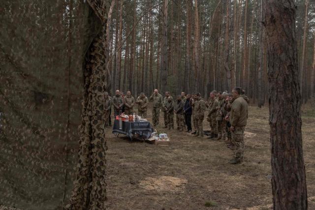 Ukrainian military members of the 33rd separate mechanised brigade pray with chaplains next to traditional cakes and other food to celebrate Orthodox Easter, in the Kharkiv region, on April 12, 2026, amid the Russian invasion of Ukraine. (Photo by Roman PILIPEY / AFP)