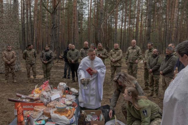 Military chaplain Mykola Bahirov (C) prays with Ukrainian military members of the 33rd separate mechanised brigade next to traditional cakes and other food to celebrate Orthodox Easter, in the Kharkiv region, on April 12, 2026, amid the Russian invasion of Ukraine. (Photo by Roman PILIPEY / AFP)