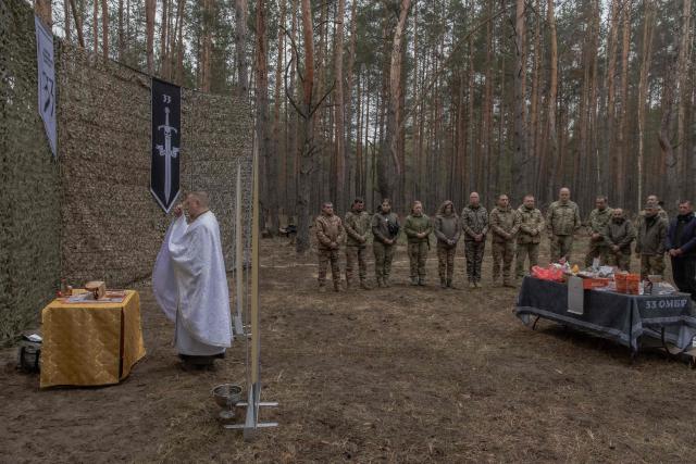Military chaplain Mykola Bahirov prays with Ukrainian military members of the 33rd separate mechanised brigade next to traditional cakes and other food to celebrate Orthodox Easter, in the Kharkiv region, on April 12, 2026, amid the Russian invasion of Ukraine. (Photo by Roman PILIPEY / AFP)