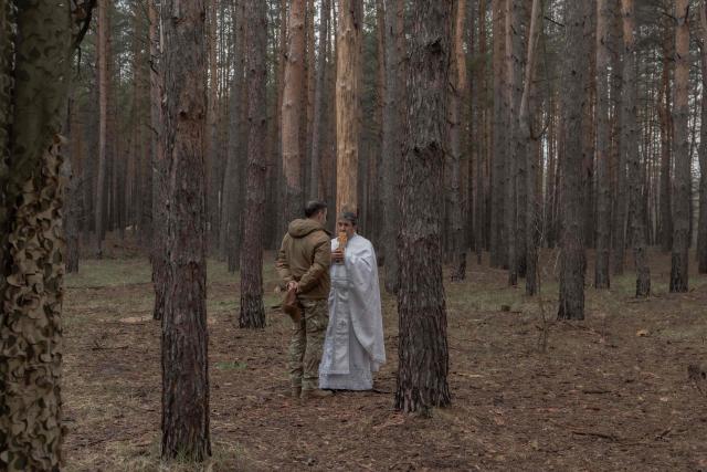 Priest Petro Nemesh speaks with a Ukrainian military member of the 33rd separate mechanised brigade during a ritual to celebrate the Orthodox Easter, in the Kharkiv region, on April 12, 2026, amid the Russian invasion of Ukraine. (Photo by Roman PILIPEY / AFP)