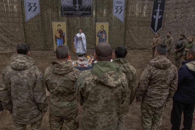 Military chaplain Mykola Bahirov prays with Ukrainian military members of the 33rd separate mechanised brigade next to traditional cakes and other food to celebrate Orthodox Easter, in the Kharkiv region, on April 12, 2026, amid the Russian invasion of Ukraine. (Photo by Roman PILIPEY / AFP)