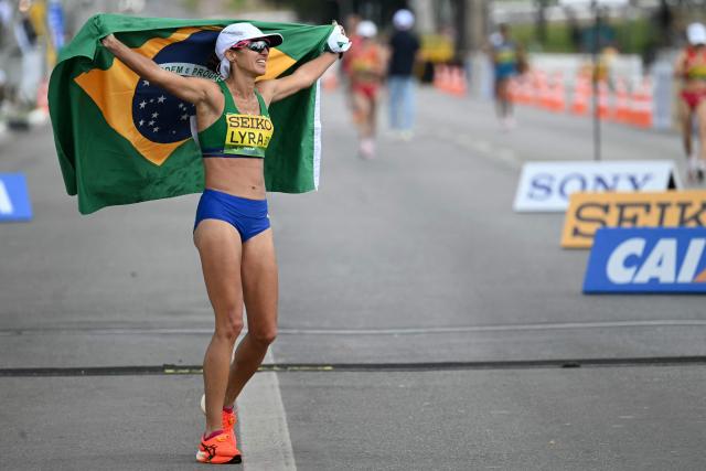 Brazil's Viviane Lyra celebrates with the national flag after getting the fifth place at the World Athletics Race Walking Team Championships women's marathon, in Brasilia, on April 12, 2026. (Photo by Evaristo SA / AFP)