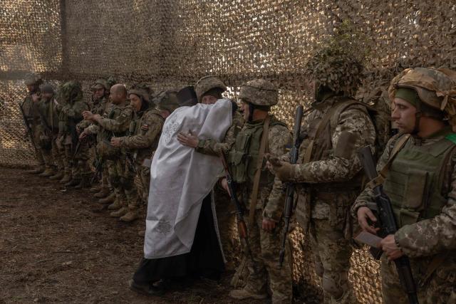 Priest Petro Nemesh embraces Ukrainian military members of the 33rd separate mechanised brigade during prayars to celebrate Orthodox Easter, in the Kharkiv region, on April 12, 2026, amid the Russian invasion of Ukraine. (Photo by Roman PILIPEY / AFP)
