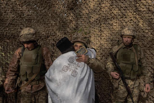 Priest Petro Nemesh embraces Ukrainian military members of the 33rd separate mechanised brigade during prayars to celebrate Orthodox Easter, in the Kharkiv region, on April 12, 2026, amid the Russian invasion of Ukraine. (Photo by Roman PILIPEY / AFP)