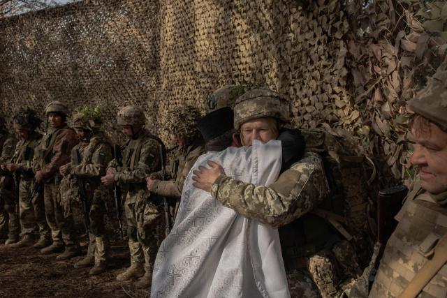 Priest Petro Nemesh embraces Ukrainian military members of the 33rd separate mechanised brigade during prayars to celebrate Orthodox Easter, in the Kharkiv region, on April 12, 2026, amid the Russian invasion of Ukraine. (Photo by Roman PILIPEY / AFP)