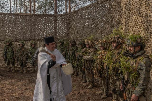 Priest Petro Nemesh blesses Ukrainian military members of the 33rd separate mechanised brigade during prayers to celebrate Orthodox Easter, in the Kharkiv region, on April 12, 2026, amid the Russian invasion of Ukraine. (Photo by Roman PILIPEY / AFP)