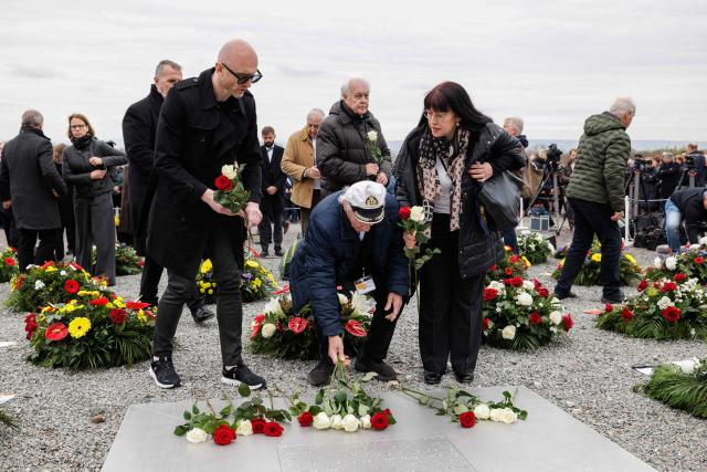 Holocaust survivor Andrej Iwanowitsch Moiseenko (C) from Belarus lays down flowers as he attends the commemoration ceremony at the memorial site of the former Nazi concentration camp Buchenwald on April 12, 2026, to mark the 81th anniversary of the liberation of the Buchenwald Nazi concentration camp near Weimar, eastern Germany. From 1937 to 1945, almost 280,000 victims of the Nazis were imprisoned in Buchenwald concentration camp and its satellite camps; more than 56,000 were murdered or died as a result of inhumane conditions. Among the prisoners were Jews, Roma, domestic political opponents of the Nazis, and forced laborers from Eastern Europe. Buchenwald is one of the most symbolically significant and best-known former concentration camps in Germany. (Photo by Jens SCHLÜTER / AFP)