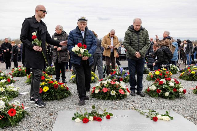 Holocaust survivor Andrej Iwanowitsch Moiseenko (C) from Belarus lays down flowers as he attends the commemoration ceremony at the memorial site of the former Nazi concentration camp Buchenwald on April 12, 2026, to mark the 81th anniversary of the liberation of the Buchenwald Nazi concentration camp near Weimar, eastern Germany. From 1937 to 1945, almost 280,000 victims of the Nazis were imprisoned in Buchenwald concentration camp and its satellite camps; more than 56,000 were murdered or died as a result of inhumane conditions. Among the prisoners were Jews, Roma, domestic political opponents of the Nazis, and forced laborers from Eastern Europe. Buchenwald is one of the most symbolically significant and best-known former concentration camps in Germany. (Photo by Jens SCHLÜTER / AFP)