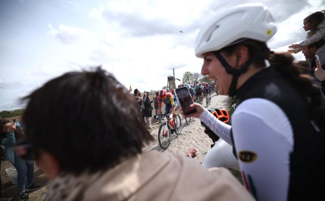 Spectators wath the pack riding a cobblestone sector during the 123rd edition of the Paris-Roubaix one-day classic cycling race, 258.3 km between Compiègne and Roubaix, northern France, on April 12, 2026. (Photo by Anne-Christine POUJOULAT / AFP)