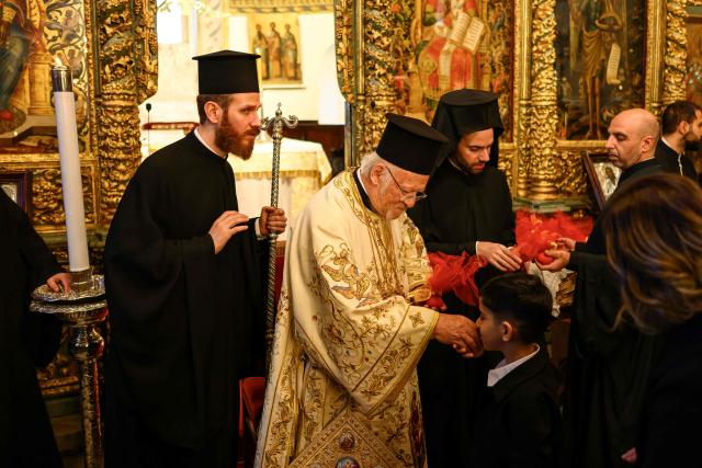 A child kisses the hand of Ecumenical Patriarch Bartholomew I (C) of Constantinople during the Orthodox Easter service at the Patriarchal Church of St. George, in Istanbul on April 12, 2026. (Photo by Yasin AKGUL / AFP)