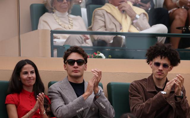 British F1 driver George Russell (C), his partner Carmen Montero (L) and Monaco's French midfielder Maghnes Akliouche applaud as they attend the Monte Carlo ATP Masters Series Tournament final tennis match between Spain's Carlos Alcaraz and Italy's Jannik Sinner on Court Rainier III at the Monte-Carlo Country Club in Roquebrune-Cap-Martin, south-eastern France on April 12, 2026. (Photo by Valery HACHE / AFP)