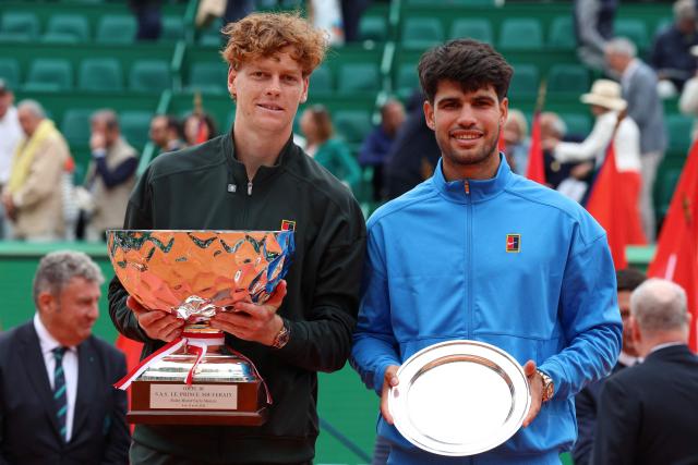Italy's Jannik Sinner (L) and Spain's Carlos Alcaraz celebrate on the podium following their Monte Carlo ATP Masters Series Tournament final tennis match on Court Rainier III at the Monte-Carlo Country Club in Roquebrune-Cap-Martin, south-eastern France on April 12, 2026. (Photo by Valery HACHE / AFP)