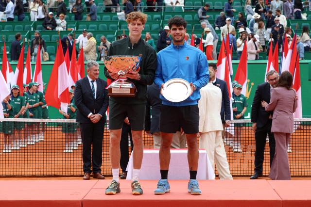Italy's Jannik Sinner (L) and Spain's Carlos Alcaraz celebrate on the podium following their Monte Carlo ATP Masters Series Tournament final tennis match on Court Rainier III at the Monte-Carlo Country Club in Roquebrune-Cap-Martin, south-eastern France on April 12, 2026. (Photo by Valery HACHE / AFP)