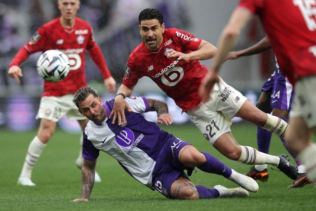 Toulouse's Norwegian midfielder #15 Aron Donnum (down) fights for the ball with Lille's French midfielder #21 Benjamin Andre (C) during the French L1 football match between Toulouse FC and Lille LOSC at the TFC Stadium in Toulouse, southwestern France, on April 12, 2026. (Photo by Valentine CHAPUIS / AFP)