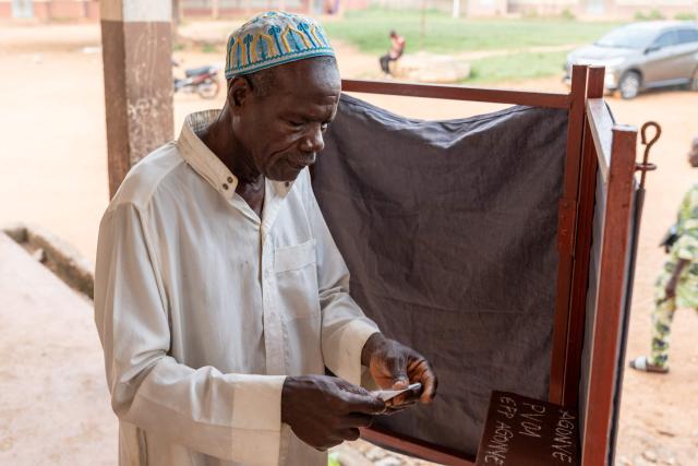 A voter folds his ballot paper after marking it in a voting booth at a polling station set up in a primary school in Lokossa on April 12, 2026 during Benin's presidential elections. (Photo by Yanick Folly / AFP)