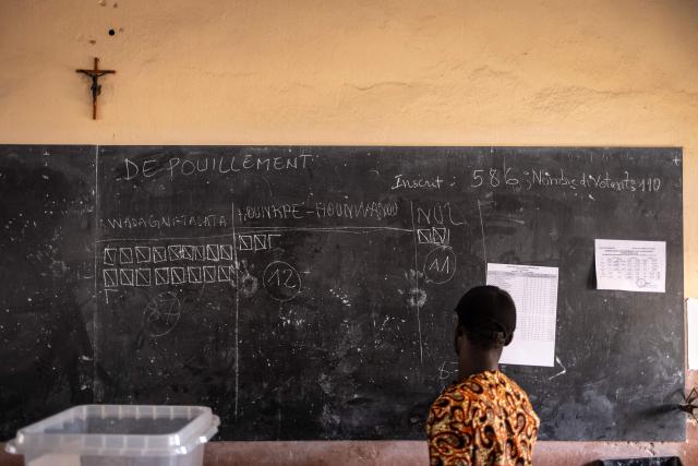 An electoral official looks at the results on a board during vote counting at a polling station in Porto-Novo, on April 12, 2026 during Benin's presidential elections. (Photo by OLYMPIA DE MAISMONT / AFP)