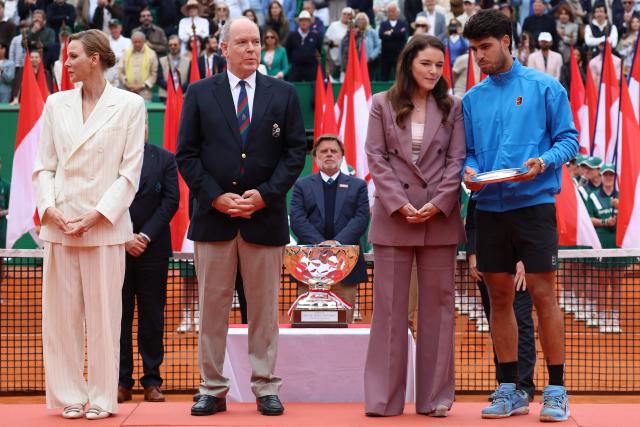 Spain's Carlos Alcaraz (R) speaks with President of the Monegasque Federation, the Rolex Masters 1000 and the Monte-Carlo Country Club Melanie de Massy (2nd R) flanked by  sPrincess Charlene of Monaco (L) and Prince Albert II of Monaco during the podium ceremony and following the Monte Carlo ATP Masters Series Tournament final tennis match against Italy's Jannik Sinner on Court Rainier III at the Monte-Carlo Country Club in Roquebrune-Cap-Martin, south-eastern France on April 12, 2026. (Photo by Valery HACHE / AFP) / / NO TABLOIDS WEB & PRINT, NO DAILY MAIL, NO DAILY MAIL GROUP, NO VOICI, NO CLOSER
