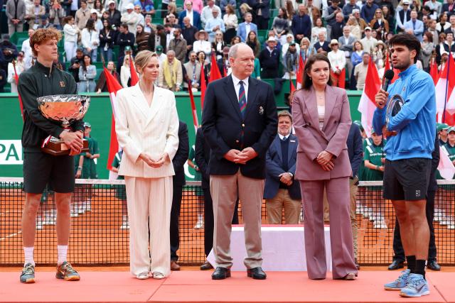 Second placed Spain's Carlos Alcaraz (R) delivers a speech flanked by President of the Monegasque Federation, the Rolex Masters 1000 and the Monte-Carlo Country Club Melanie de Massy (2nd R), Prince Albert II of Monaco (C), Princess Charlene of Monaco (2nd L) and winner Italy's Jannik Sinner during the podium ceremony and following the Monte Carlo ATP Masters Series Tournament final tennis match on Court Rainier III at the Monte-Carlo Country Club in Roquebrune-Cap-Martin, south-eastern France on April 12, 2026. (Photo by Valery HACHE / AFP) / / NO TABLOIDS WEB & PRINT, NO DAILY MAIL, NO DAILY MAIL GROUP, NO VOICI, NO CLOSER