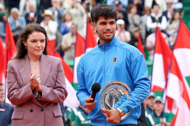 Second placed Spain's Carlos Alcaraz (R) delivers a speech flanked by President of the Monegasque Federation, the Rolex Masters 1000 and the Monte-Carlo Country Club Melanie de Massy during the podium ceremony and following the Monte Carlo ATP Masters Series Tournament final tennis match on Court Rainier III at the Monte-Carlo Country Club in Roquebrune-Cap-Martin, south-eastern France on April 12, 2026. (Photo by Valery HACHE / AFP) / / NO TABLOIDS WEB & PRINT, NO DAILY MAIL, NO DAILY MAIL GROUP, NO VOICI, NO CLOSER