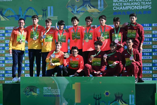 The teams of Japan (C), Spain, and China pose with their gold, silver and bronze medals respectively during the award ceremony of the World Athletics Race Walking Team Championships men's team half-marathon, in Brasilia, on April 12, 2026. (Photo by Evaristo SA / AFP)