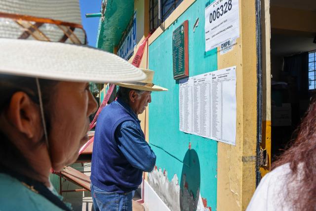 Men look at a chart outside a polling station in the district of Chiguata, an agricultural area located some 25 kilometres from Arequipa, Peru on April 12, 2026, during general elections. Peruvians will elect a new president from a record field of 35 candidates to lead a country plagued by organized crime and chronic political instability. (Photo by Diego RAMOS / AFP)
