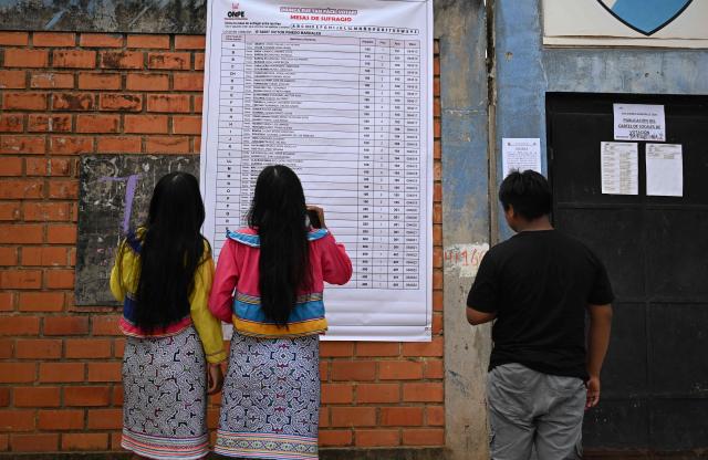 Women check for their polling station during the general election in San Pablo de Tushmo, near Pucallpa, Uyacali region, Peru on April 12, 2026. Peruvians head to the polls to elect its ninth president in a decade, from a record field of 35 candidates, with crime-weary voters seemingly poised to extend the tide of conservative governments sweeping Latin America. (Photo by Hugo Alejos / AFP)