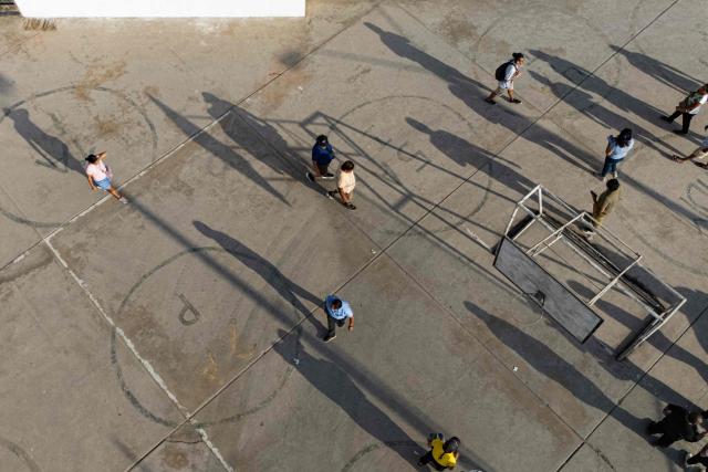 Aerial view people walking at the Fe y Alegria 65 school polling station in Pamplona Alta, San Juan de Miraflores district on the outskirts of Lima on April 12, 2026. Peruvians head to the polls to elect its ninth president in a decade, from a record field of 35 candidates, with crime-weary voters seemingly poised to extend the tide of conservative governments sweeping Latin America. (Photo by Ernesto BENAVIDES / AFP)