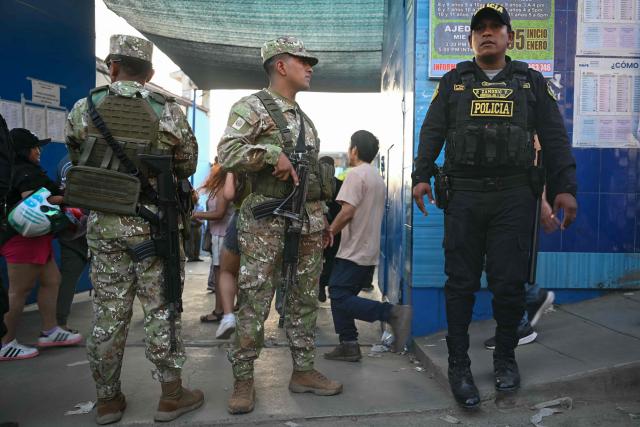 Members of Peru’s police force stand guard at a school polling station in Pamplona Alta, in the San Juan de Miraflores district on the outskirts of Lima, on April 12, 2026. Hours-long delays marred Peru's presidential and legislative elections on April 12, as voters sought to end political chaos that has seen a string of presidents ousted or jailed. (Photo by Ernesto BENAVIDES / AFP)