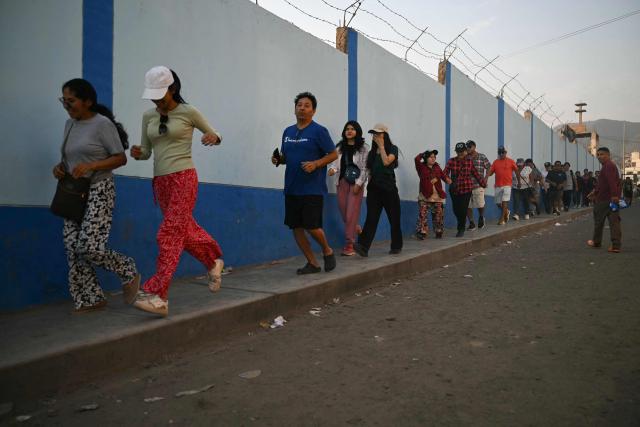 People run to cast their votes at a school polling station in Pamplona Alta, in the San Juan de Miraflores district on the outskirts of Lima, on April 12, 2026. Hours-long delays marred Peru's presidential and legislative elections on April 12, as voters sought to end political chaos that has seen a string of presidents ousted or jailed. (Photo by Ernesto BENAVIDES / AFP)