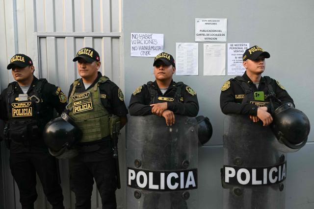 Members of Peru’s police force stand guard at the Virgen de la Asuncion school, where the polling station is closed, in Pamplona Alta, in the San Juan de Miraflores district on the outskirts of Lima, on April 12, 2026. Hours-long delays marred Peru's presidential and legislative elections on April 12, as voters sought to end political chaos that has seen a string of presidents ousted or jailed. (Photo by Ernesto BENAVIDES / AFP)