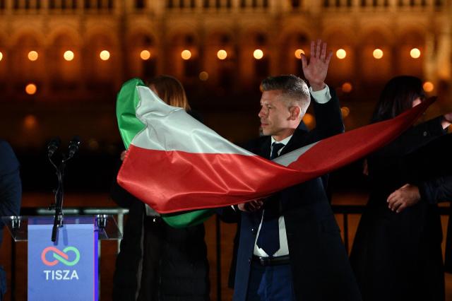 Peter Magyar, leader of the pro-European conservative TISZA party, waves the national flag during celebrations at the election night party in Budapest after the general election in Hungary, on April 12, 2026. The party of conservative Peter Magyar won a two-thirds parliamentary majority in Sunday's Hungarian elections in a clear defeat for nationalist long-time Prime Minister Viktor Orban, according to near-complete results. (Photo by Ferenc ISZA / AFP)