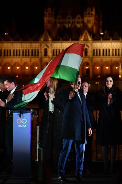 Peter Magyar, leader of the pro-European conservative TISZA party, waves the national flag during celebrations at the election night party on the banks of the Danube river with the Parliament building in the background, in Budapest after the general election in Hungary, on April 12, 2026. The party of conservative Peter Magyar won a two-thirds parliamentary majority in Sunday's Hungarian elections in a clear defeat for nationalist long-time Prime Minister Viktor Orban, according to near-complete results. (Photo by Ferenc ISZA / AFP)