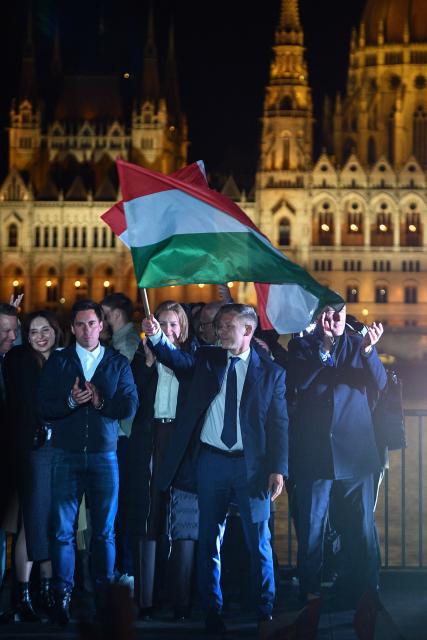 Peter Magyar, leader of the pro-European conservative TISZA party, waves the national flag during celebrations at the election night party on the banks of the Danube river with the Parliament building in the background, in Budapest after the general election in Hungary, on April 12, 2026. The party of conservative Peter Magyar won a two-thirds parliamentary majority in Sunday's Hungarian elections in a clear defeat for nationalist long-time Prime Minister Viktor Orban, according to near-complete results. (Photo by Ferenc ISZA / AFP)