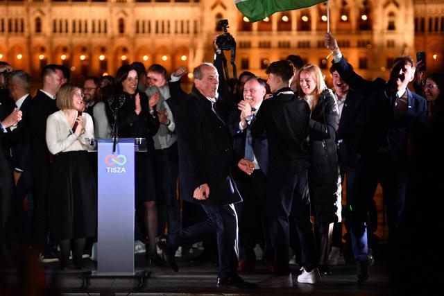 Members of the pro-European conservative TISZA party celebrate at their election night party on the banks of the Danube river with the Parliament building in the background, in Budapest during the general election in Hungary, on April 12, 2026. The TISZA party, of conservative Peter Magyar, won a two-thirds parliamentary majority in Sunday's Hungarian elections in a clear defeat for nationalist long-time Prime Minister Viktor Orban, according to near-complete results. (Photo by Ferenc ISZA / AFP)