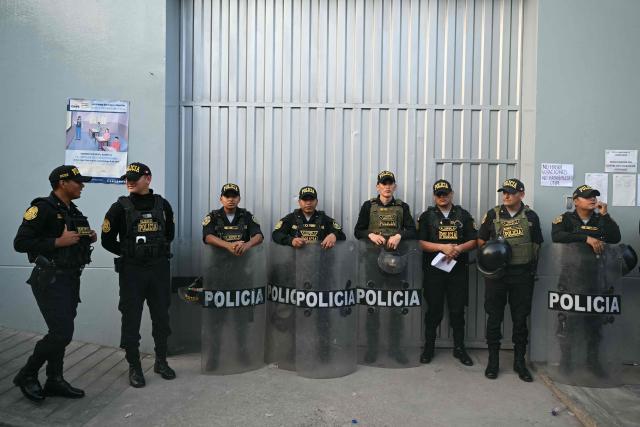 Members of Peru’s police force stand guard at the Virgen de la Asuncion school, where the polling station is closed, in Pamplona Alta, in the San Juan de Miraflores district on the outskirts of Lima, on April 12, 2026. Hours-long delays marred Peru's presidential and legislative elections on April 12, as voters sought to end political chaos that has seen a string of presidents ousted or jailed. (Photo by Ernesto BENAVIDES / AFP)