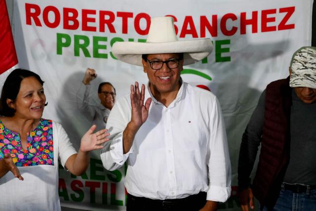 Peru's presidential candidate Roberto Sanchez (C) of the Juntos por el Peru party, waves as he gives a speech following the first results of the presidential election in Lima on April 12, 2026. Right-wing candidate Keiko Fujimori led exit polls following Peru's troubled presidential election on April 12, 2026, but failed to avoid a runoff after a tight vote marred by irregularities and a police raid on the country's election authority. (Photo by Luis ROBAYO / AFP)