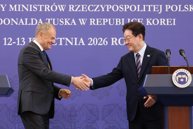 South Korean President Lee Jae Myung (R) shakes hands with Poland's Prime Minister Donald Tusk during a joint press conference at the presidential Blue House in Seoul on April 13, 2026.  (Photo by Chung Sung-Jun / POOL / AFP)