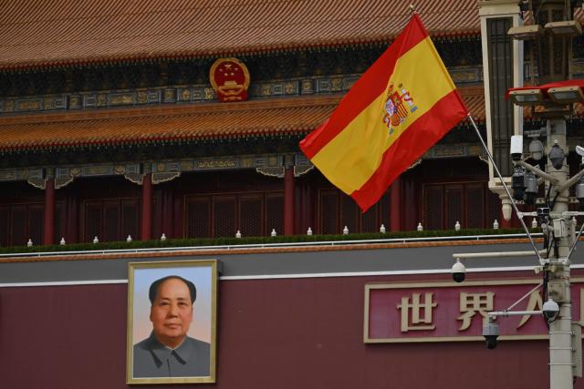 The national flag of Spain hangs in front of the portrait of late communist leader Mao Zedong at Tiananmen Gate during a visit by Spain's Prime Minister Pedro Sanchez in Beijing on April 13, 2026. (Photo by Pedro PARDO / AFP)