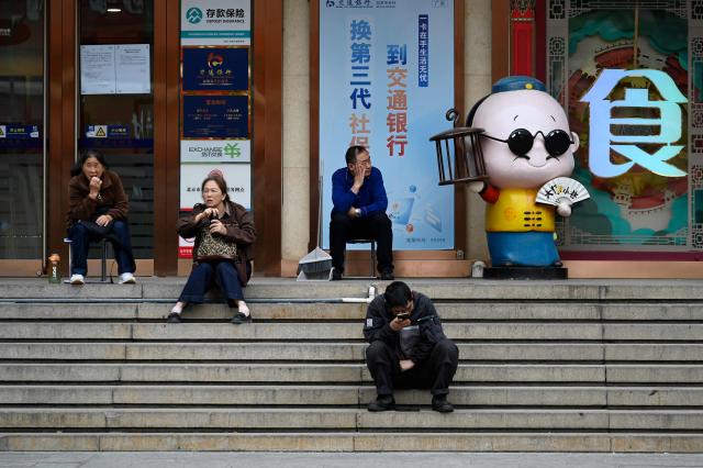People sit outside a restaurant in Beijing on April 13, 2026. (Photo by WANG Zhao / AFP)