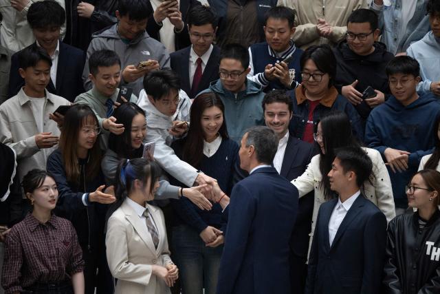 Spain's Prime Minister Pedro Sanchez (C) shakes hands with students after a group photo at Tsinghua University in Beijing on April 13, 2026. Sanchez called China's trade imbalance with the European Union "unsustainable" on April 13, as he began a three-day visit to Beijing where he hopes to strengthen economic ties. (Photo by ANDRES MARTINEZ CASARES / POOL / AFP)