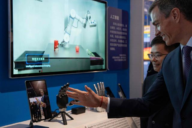 Spain's Prime Minister Pedro Sanchez checks a robotic hand during a visit to the University of Chinese Academy of Sciences in Beijing on April 13, 2026. Sanchez called China's trade imbalance with the European Union "unsustainable" on April 13, as he began a three-day visit to Beijing where he hopes to strengthen economic ties. (Photo by ANDRES MARTINEZ CASARES / POOL / AFP)