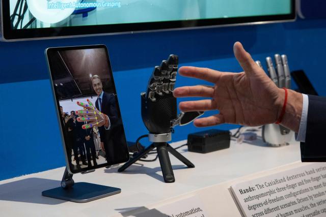 TOPSHOT - Spain's Prime Minister Pedro Sanchez checks a robotic hand during a visit to the University of Chinese Academy of Sciences in Beijing on April 13, 2026. Sanchez called China's trade imbalance with the European Union "unsustainable" on April 13, as he began a three-day visit to Beijing where he hopes to strengthen economic ties. (Photo by ANDRES MARTINEZ CASARES / POOL / AFP)