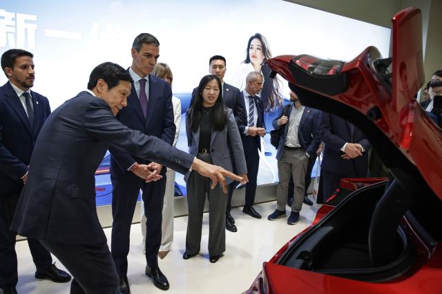 Founder, Chairman & CEO of Xiaomi, Lei Jun (2nd L), shows the trunk of a Xiaomi SU7 car to Spain's Prime Minister Pedro Sanchez (C) at the Xiaomi headquarters Beijing on April 13, 2026. Sanchez called China's trade imbalance with the European Union "unsustainable" on April 13, as he began a three-day visit to Beijing where he hopes to strengthen economic ties. (Photo by ANDRES MARTINEZ CASARES / POOL / AFP)