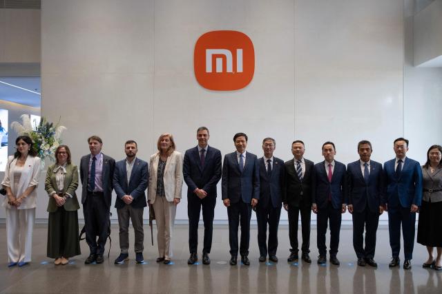 Spain's Prime Minister Pedro Sanchez (C) and Founder, Chairman & CEO of Xiaomi, Lei Jun (centre, R), pose for a group photo at the Xiaomi headquarters Beijing on April 13, 2026. Sanchez called China's trade imbalance with the European Union "unsustainable" on April 13, as he began a three-day visit to Beijing where he hopes to strengthen economic ties. (Photo by ANDRES MARTINEZ CASARES / POOL / AFP)