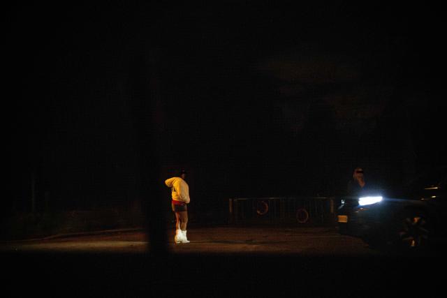 (FILES) Sex workers wait for clients standing in a street in the Bois de Boulogne, west of Paris, on March 30, 2024. A 2016 law in France criminalised the purchase of sexual services, reclassifying sex workers as victims and making clients liable to a fine of 1,500 euros. Ten years after the law, the organisations Federation Parapluie rouge, Amnesty International, Acceptess-T and the NousToutes collective are calling in a private member’s bill (PPL) to decriminalise sex work. (Photo by JULIEN DE ROSA / AFP)