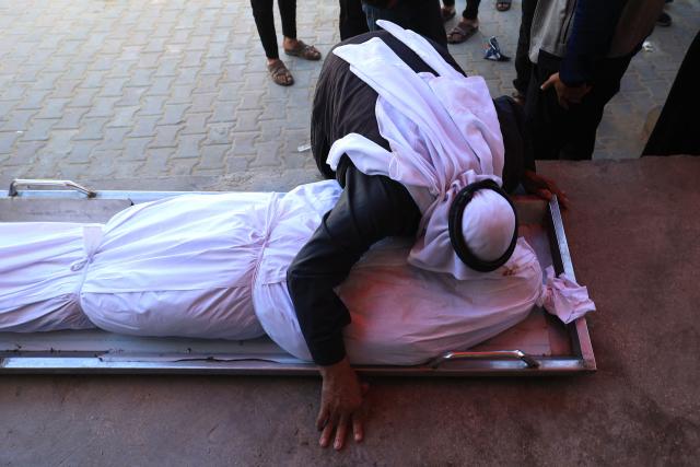 A Palestinian man kisses a shrouded body during the funeral of Palestinians who, according to a medic, were killed the night before in an Israeli strike at al-Aqsa Martyrs Hospital in Deir al Balah in the central Gaza Strip on April 13, 2026. Both Israel and Hamas have accused each other of breaching the US-backed truce, which has largely halted the two-year war that devastated the enclave of 2.2 million. A delegation from Hamas was set to hold talks with Egyptian mediators in Cairo on April 12, 2026, to address alleged Israeli violations of the Gaza ceasefire, according to two officials from the Palestinian group. (Photo by Eyad Baba / AFP)